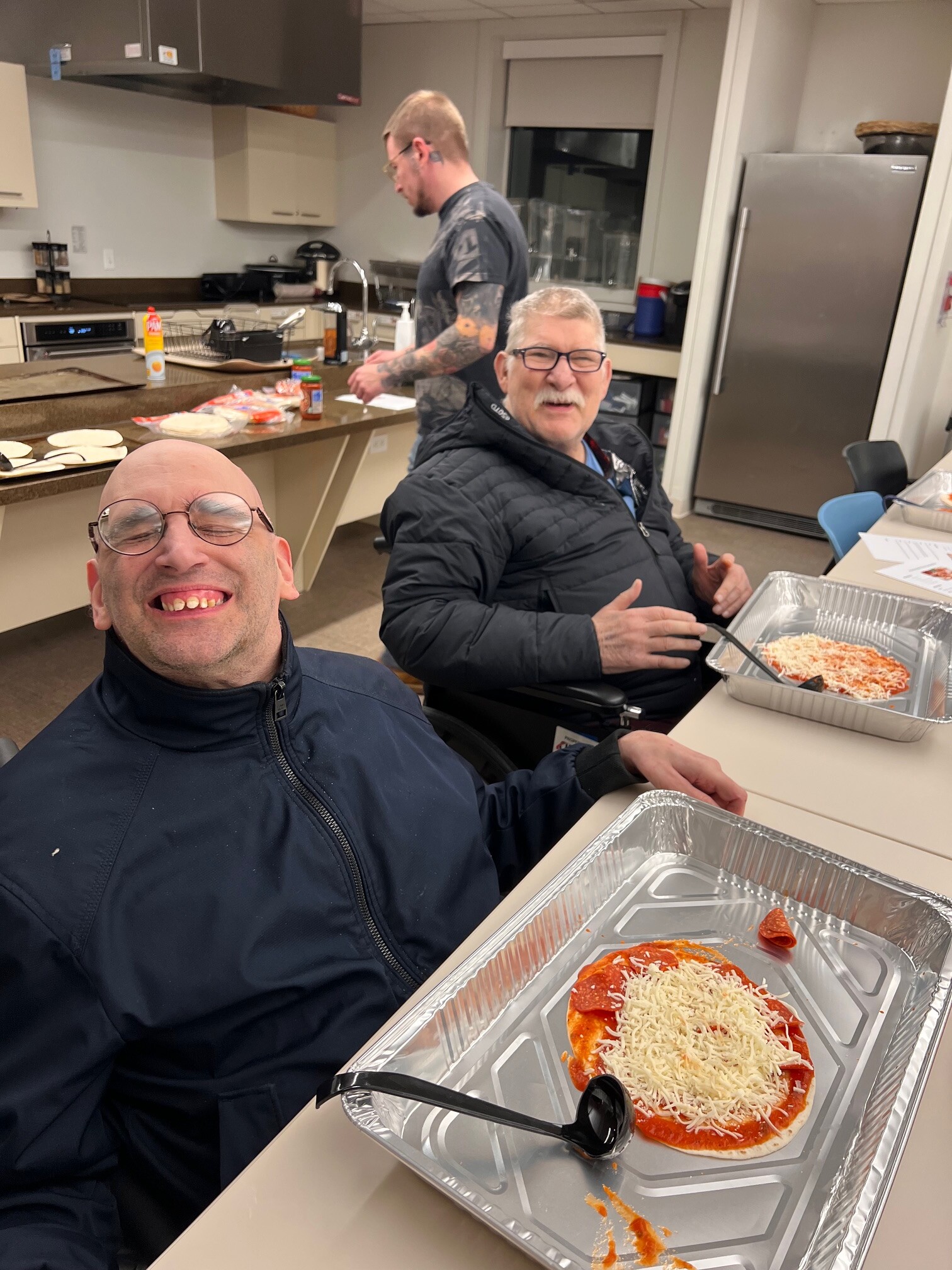 A photo of two CEL Guy's Night members smiling while participating in a cooking pizza activity.