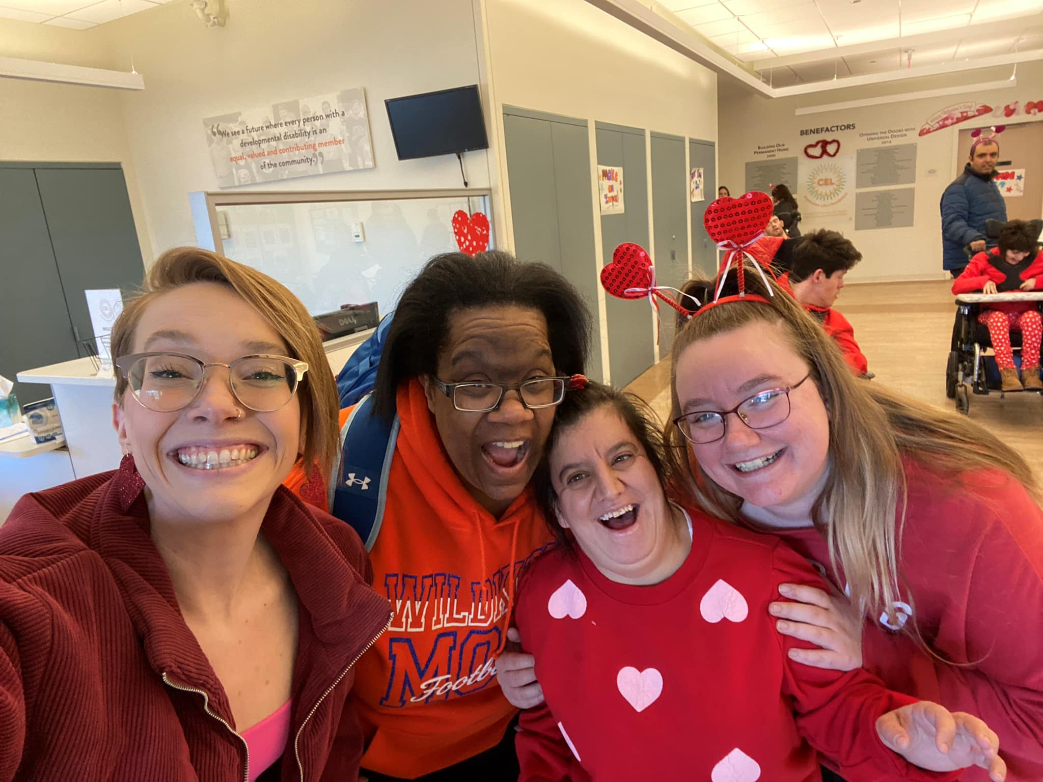 CEL REACH member with staff smiling wearing red.