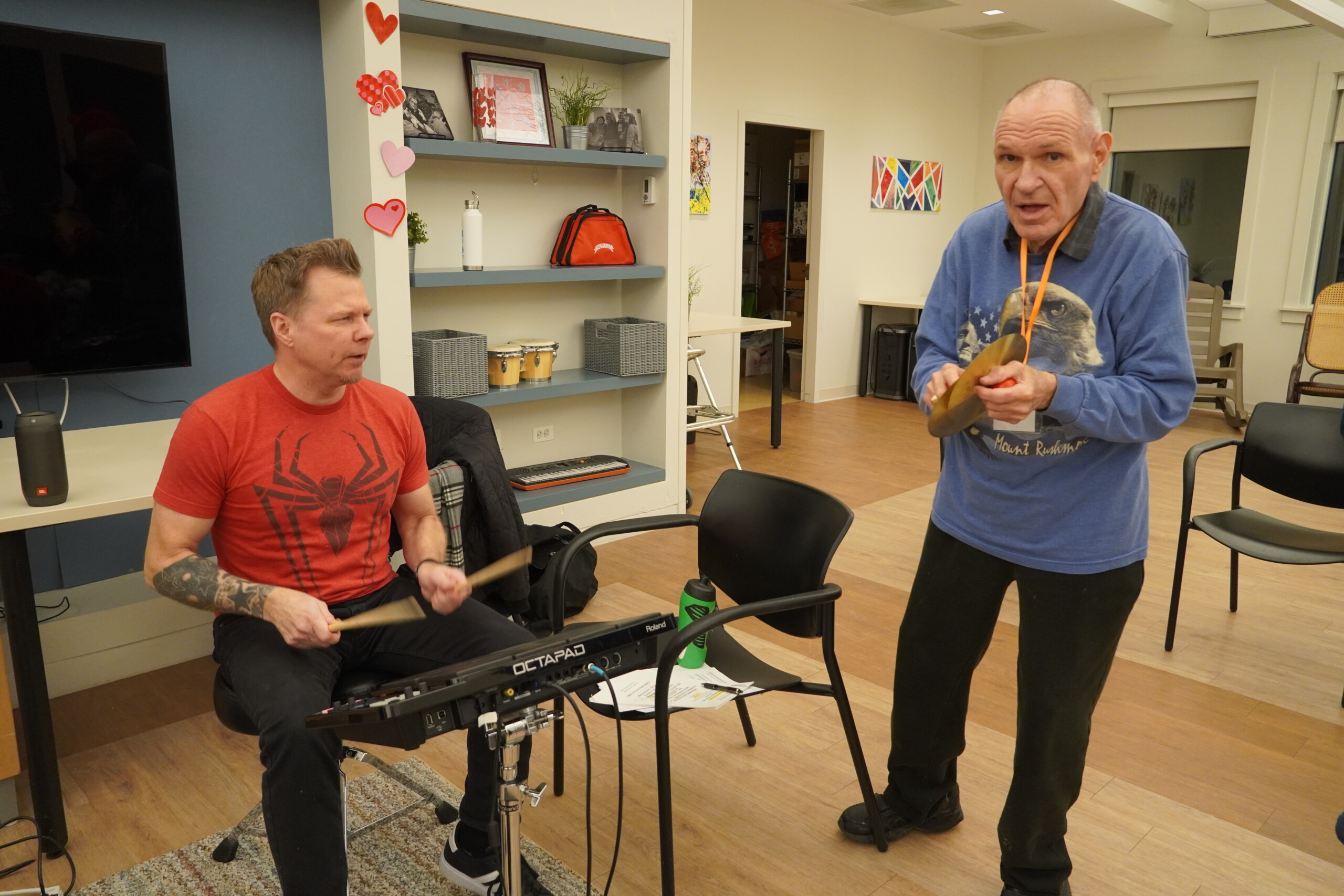 A picture of CEL member dancing as volunteer drums up beat during Friday Night Music.